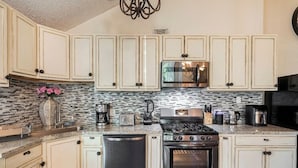 A kitchen with white cabinets, a stainless steel stove, a microwave, and a dishwasher.