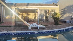 Il s’agit d’une propriété résidentielle dotée d’une piscine, d’un patio couvert avec une chaise et d’un petit jardin.