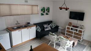 Un espace de vie compact comprenant un coin cuisine, un canapé, une télévision et un coin repas.
