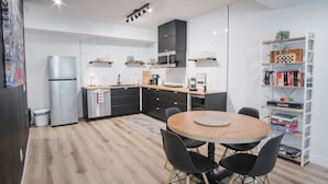Een moderne keuken met een centraal eiland, zwarte kasten, en een eethoek met een ronde tafel en stoelen.