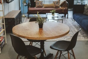 Una mesa de comedor redonda de madera con dos sillas negras, una planta en maceta y una estantería en un salón.