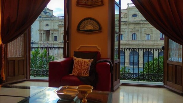 A room with a red armchair, a glass coffee table, and two wall-mounted fans.