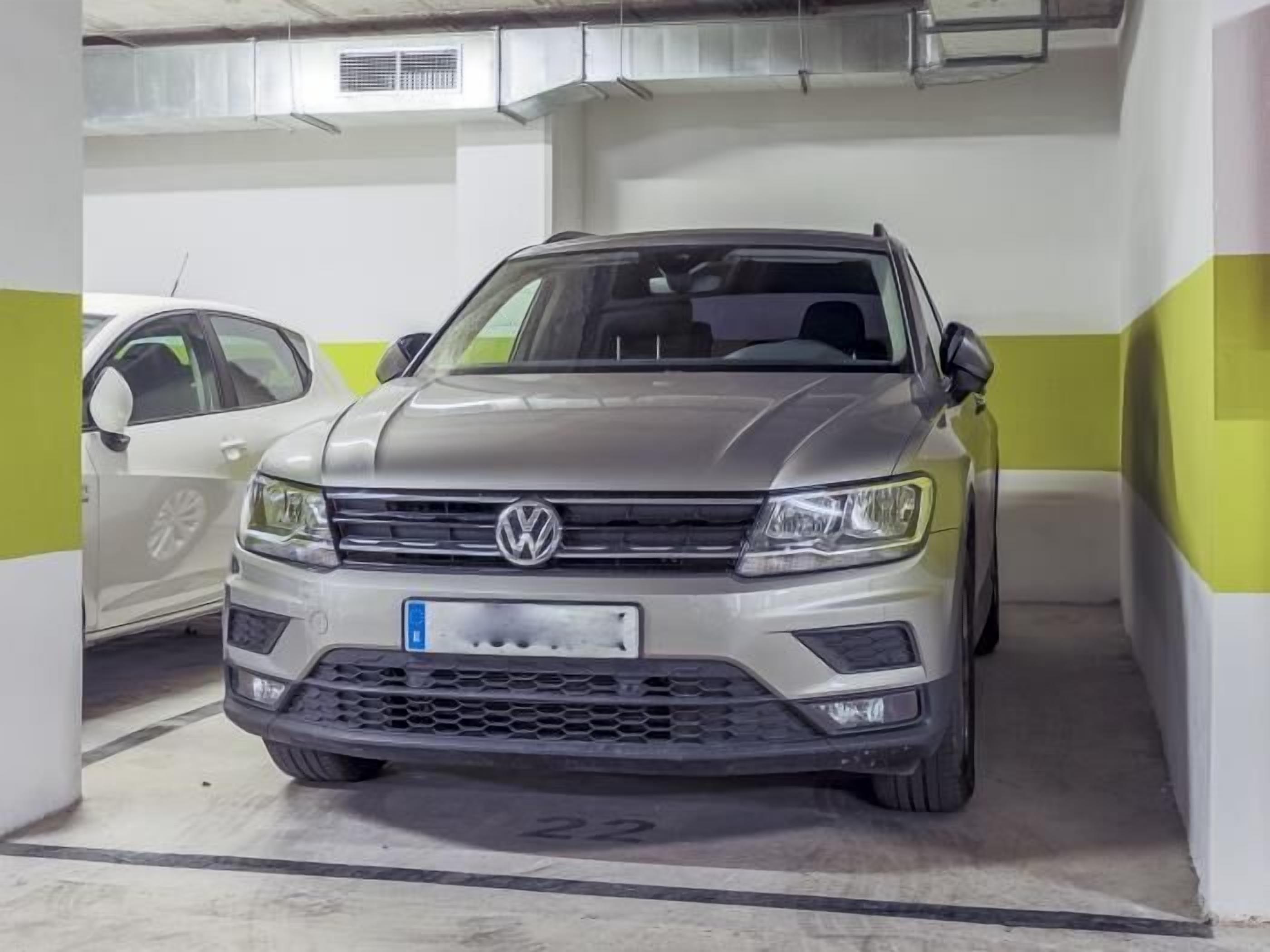 Un cotxe Volkswagen estacionat en un pàrquing amb una paret de bandes blanques i verdes.