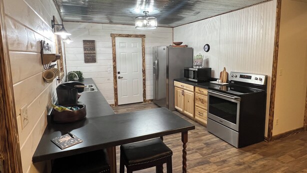 A compact kitchen with a wooden table, two stools, a refrigerator, a microwave, and an oven. - Charming 3-bedroom house in Decatur City, Minutes from Little River Lake. (Decatur City)