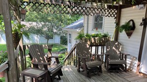 A wooden deck with Adirondack chairs and a pergola with string lights. - Charming 3-bedroom house in Decatur City, Minutes from Little River Lake. (Decatur City)