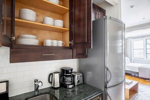 Una cocina moderna con armarios de madera oscura, azulejos blancos y un refrigerador de acero inoxidable.