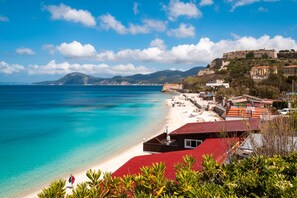 Une ville côtière avec une plage, des bâtiments et une colline sur laquelle se trouvent des ruines.