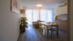 Un espacio habitable compacto con comedor, kitchenette y un amplio ventanal con cortinas.