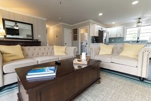 Relax in this stylish living room with a tufted sofa, coffee table, and large mirror.