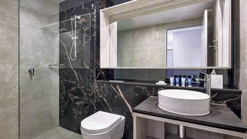 Une salle de bain moderne avec une douche à parois de verre, des toilettes blanches et un meuble-lavabo doté d’un grand miroir et d’un évier.