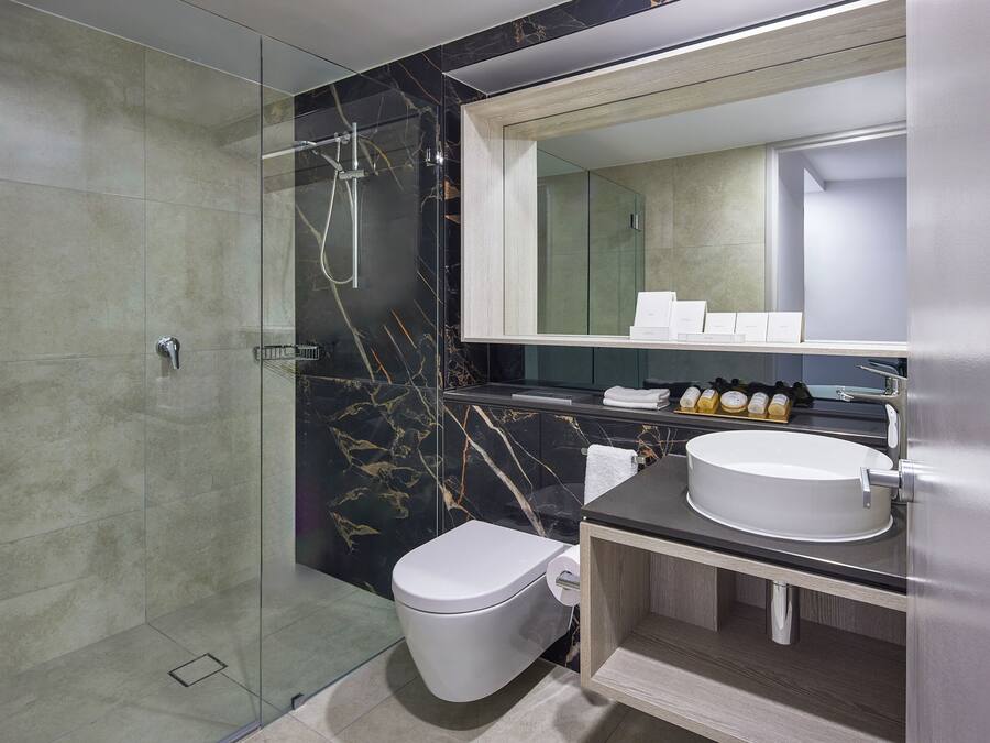 A modern bathroom with a glass-enclosed shower, a white toilet, a vanity with a sink, and a mirror above the sink.