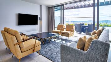 A modern living room with a flat-screen TV, a coffee table, and seating including a sofa and armchairs.