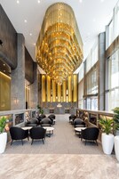 A spacious lobby with a modern chandelier, seating area, and large windows.