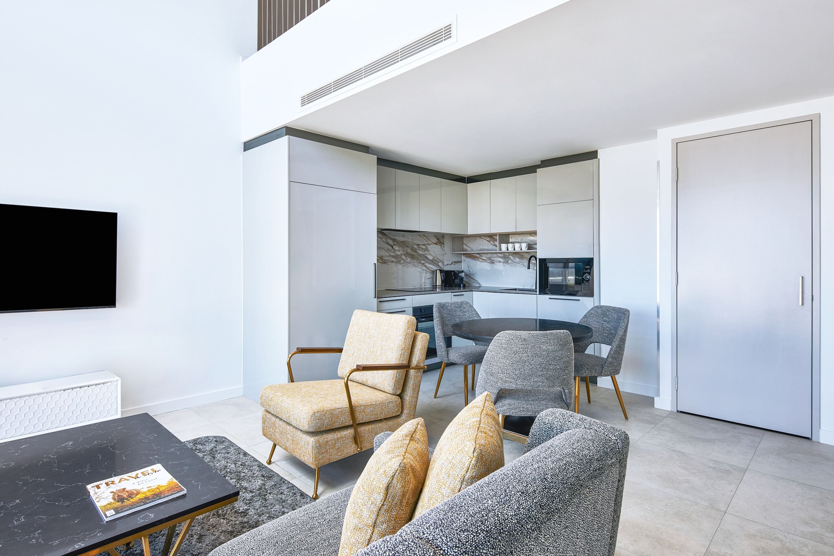 A modern living room with a black coffee table, a sofa, and a dining area with a table and chairs.