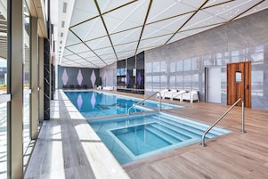 An indoor swimming pool with a modern design, including a geometric ceiling and a wooden floor.