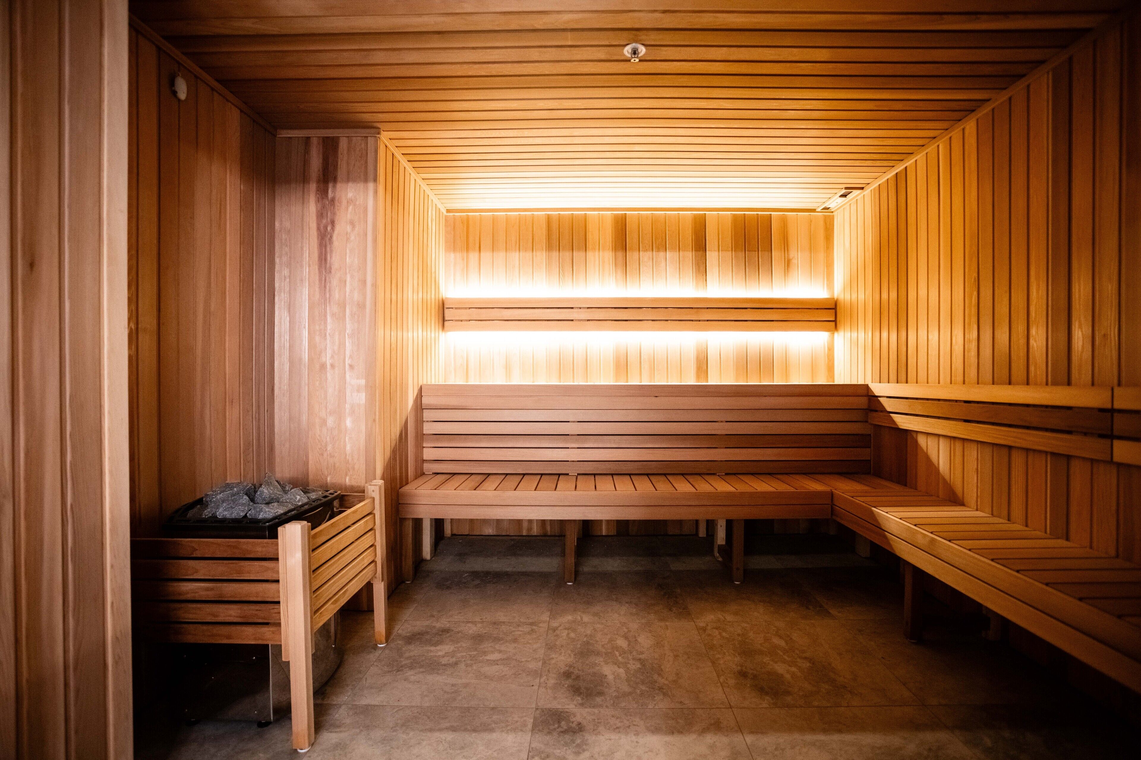 A sauna with wooden benches and a bench with a trash bin.