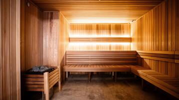 A sauna with wooden benches and a bench with a trash bin.