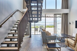 A modern interior with a staircase, a sofa, and a table.