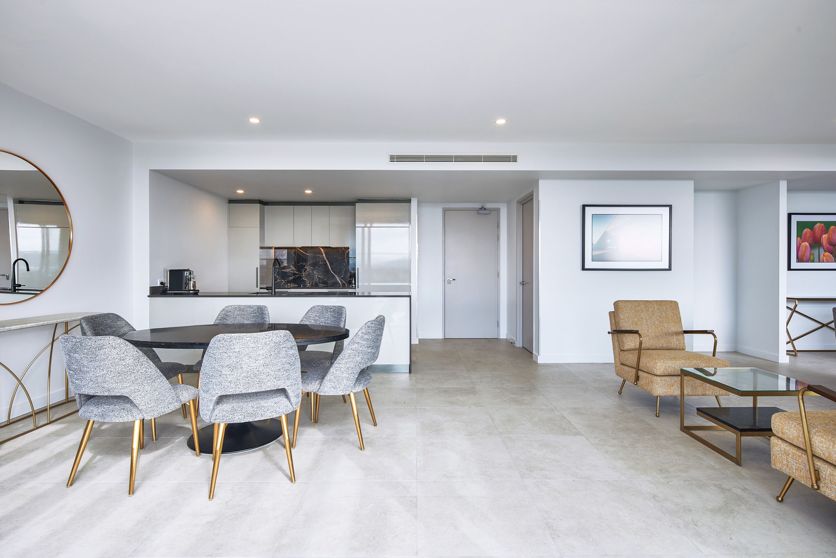 A modern living room with a dining area, a kitchen, and a seating area with a glass table and chairs.