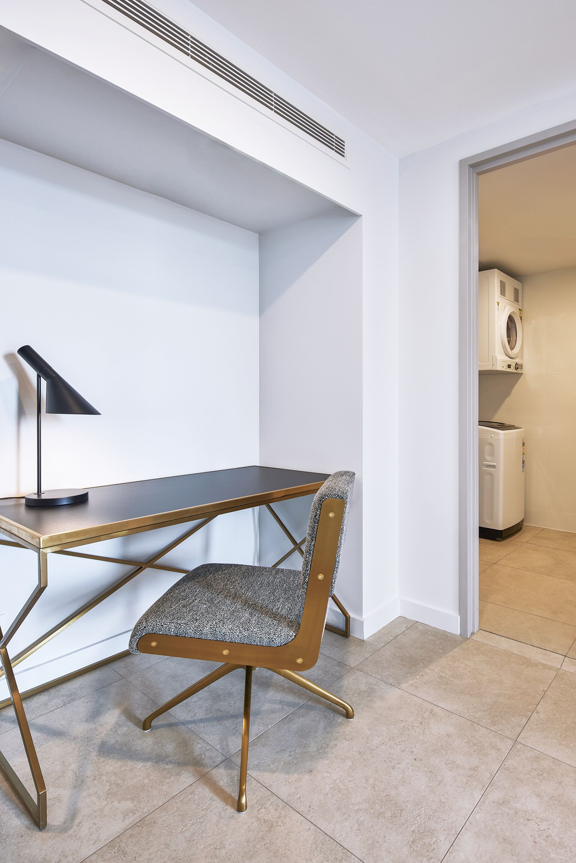 A modern room with a desk, chair, and a laundry area.