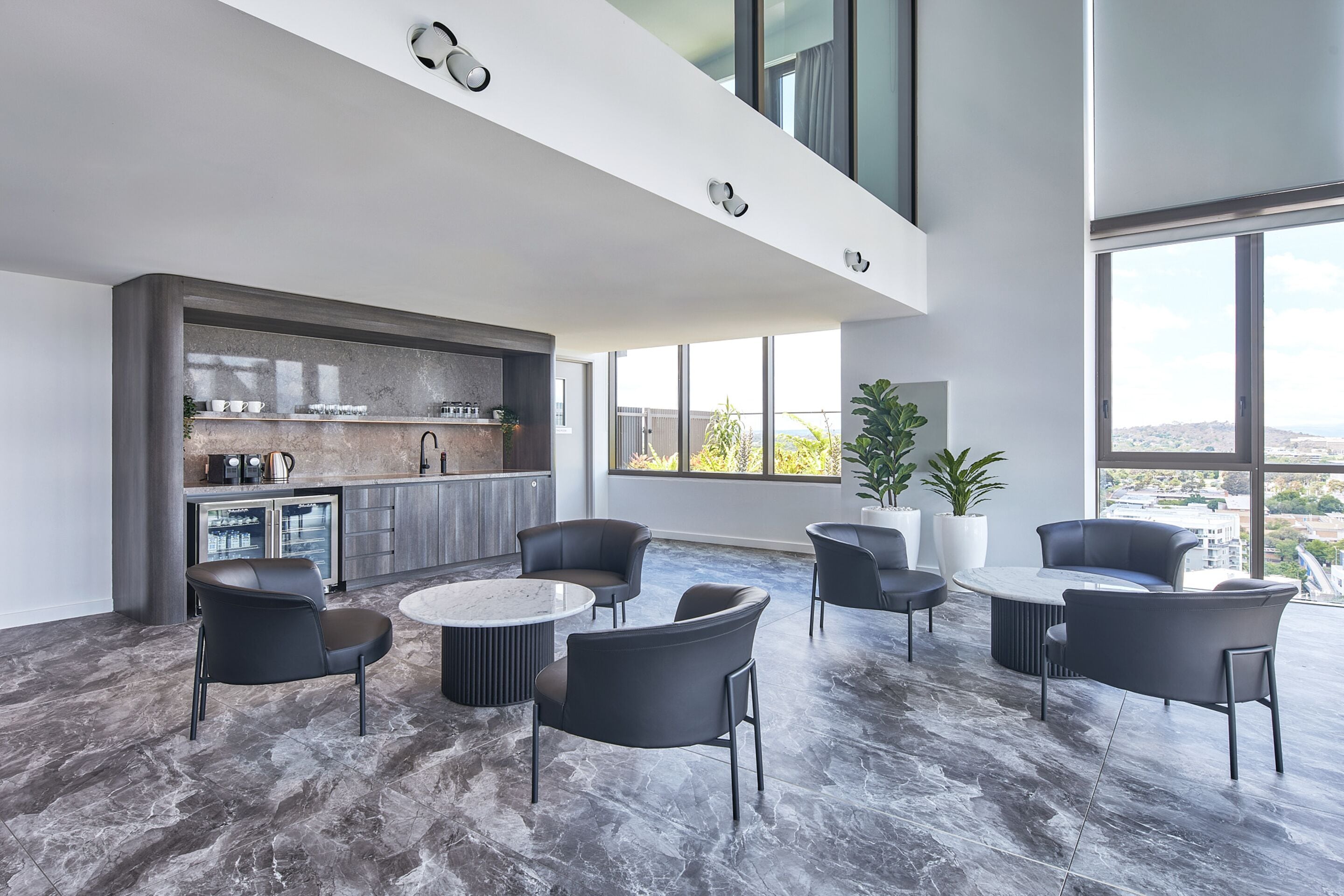 Amplia sala de estar con muebles modernos y una cocina al fondo.