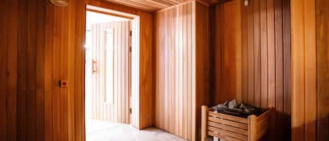 Un intérieur en bois avec un banc de sauna et une porte donnant sur un espace lumineux.