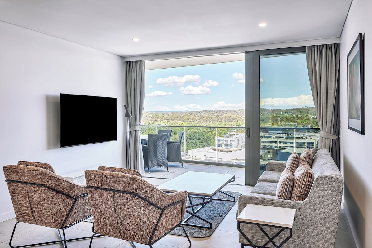 A modern living room with a sofa, chairs, a coffee table, and a TV mounted on the wall.