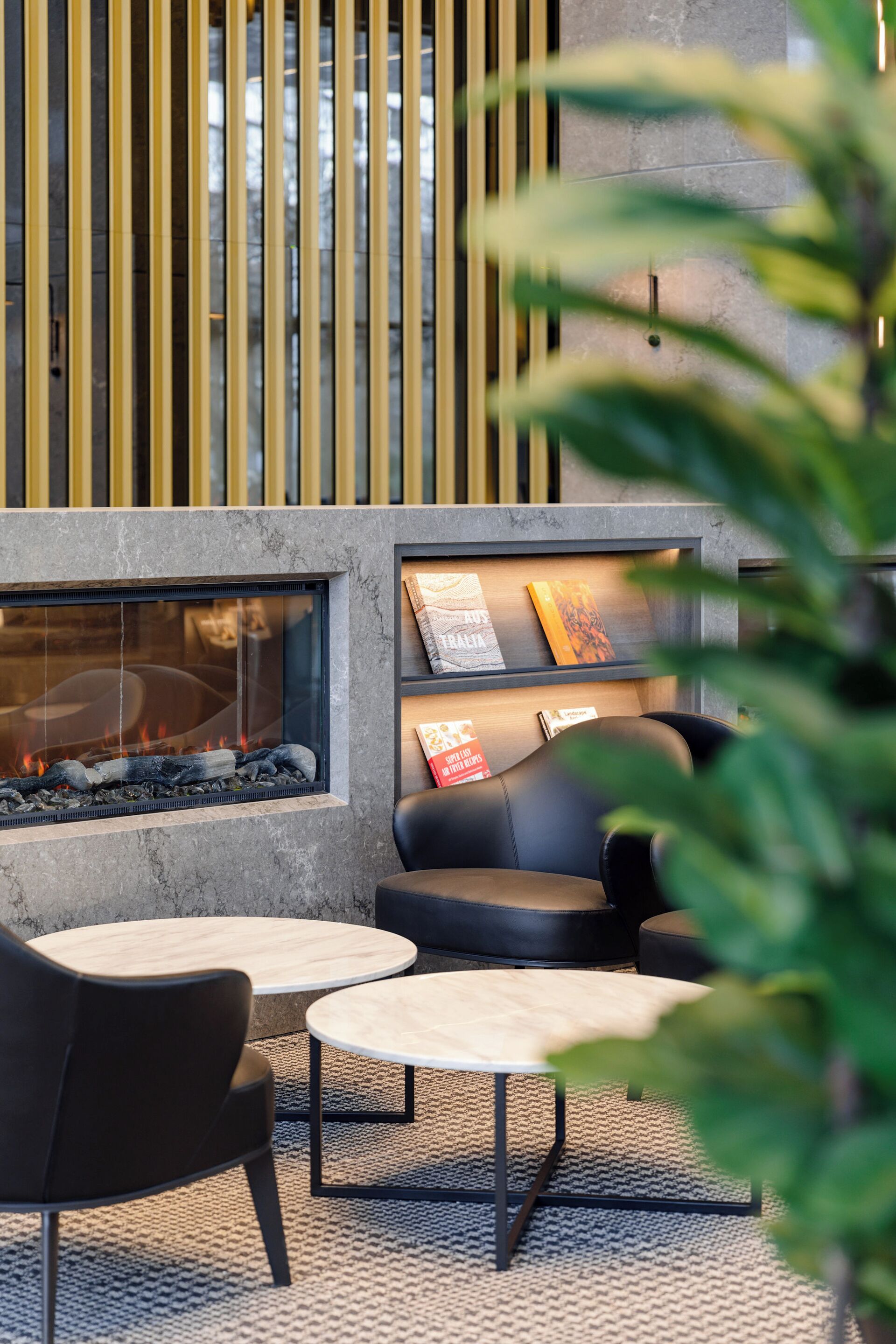 A modern lounge area with a fireplace, seating, and a bookshelf.