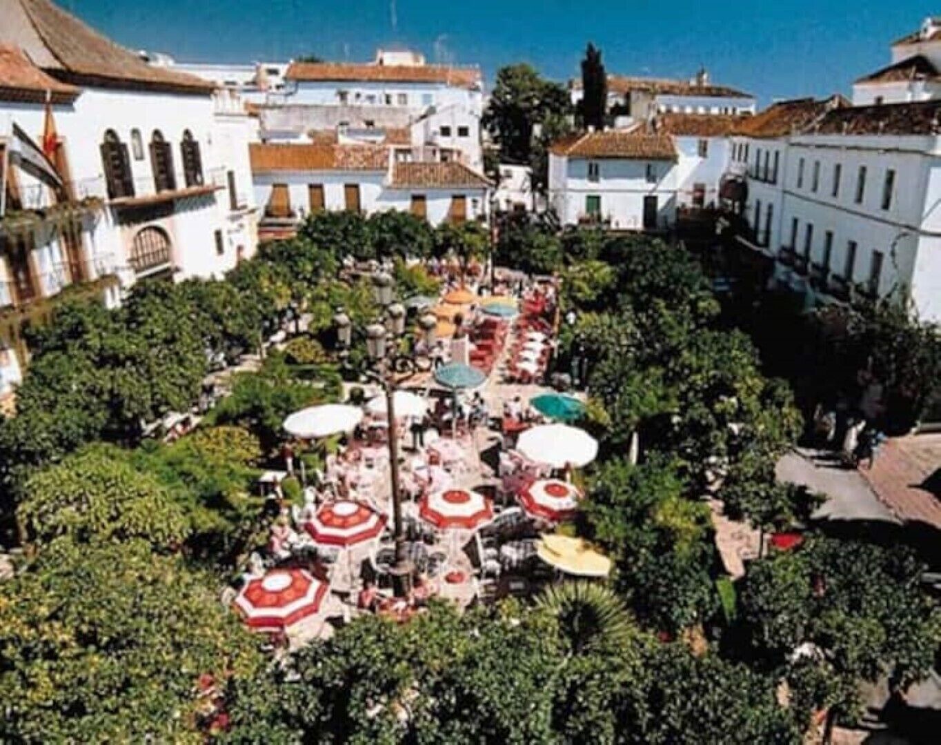 An aerial view of a courtyard with multiple outdoor seating areas, surrounded by trees and buildings with traditional architecture.