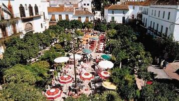 An aerial view of a courtyard with multiple outdoor seating areas, surrounded by trees and buildings with traditional architecture.