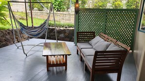 A patio with a hammock, a wooden table, and a sofa.