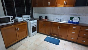 A kitchen with wooden cabinets, a microwave, a stove, and a sink.