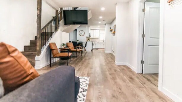 A spacious living room with a staircase, a dining area, and a kitchen in the background.