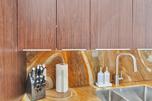 Una cocina con armarios de madera, salpicadero de mármol, un fregadero y un juego de cuchillos.