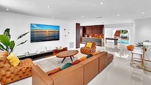 A modern living room with a large sofa, a coffee table, and a TV mounted on the wall.