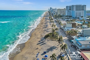 Relax on the beach with sun loungers and umbrellas, surrounded by palm trees and the sound of the ocean.