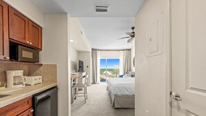 A hotel room with a kitchenette, a desk, a bed, and a balcony with a view. - Studio Sandestin Resort, 4 mins walk to beach, sleeps 3-4 (Miramar Beach)