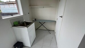 A compact kitchen with a window, a small countertop, and a drying rack. - Cheerful 3 bedroom  with free parking (Auckland)