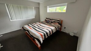 A bedroom with a bed, a window, and a ceiling vent. - Cheerful 3 bedroom  with free parking (Auckland)