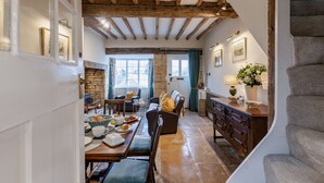Un comedor acogedor con una mesa de madera lista para una comida, una chimenea y vistas del exterior a través de un ventanal grande.
