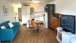 Um espaço compacto com cozinha compacta, área de jantar, sofá, televisão e ventoinha de teto.