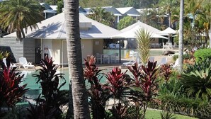 Um resort com piscina, palmeiras e espreguiçadeiras.