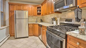 A kitchen with wooden cabinets, stainless steel appliances, a microwave, and a stove. - Hoboken Condo: Walk to Public Transit! (Hoboken)