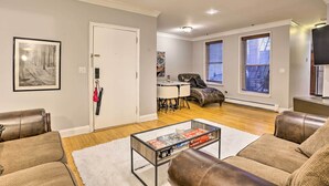 A modern living room with leather sofas, a glass coffee table, and hardwood flooring. - Hoboken Condo: Walk to Public Transit! (Hoboken)