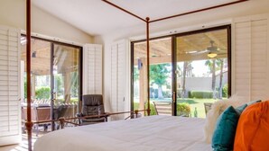 Une chambre avec un grand lit, une chaise et une vue sur un jardin, accessible par une porte coulissante.