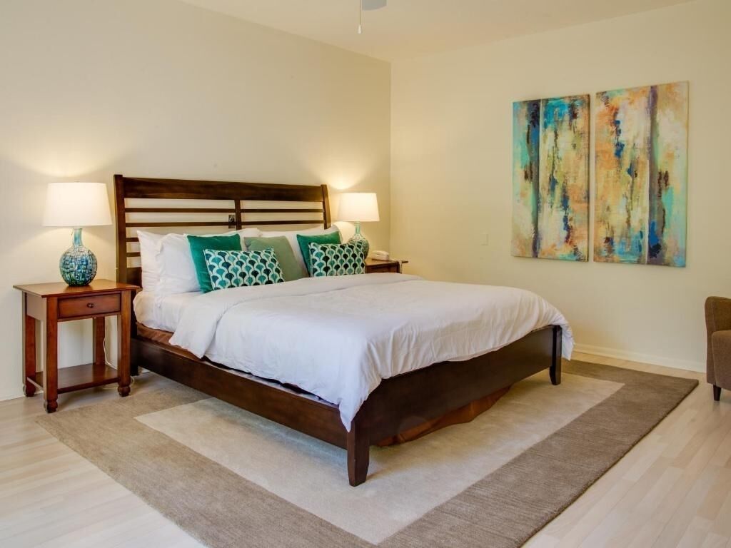 A bedroom with a wooden bed, two bedside tables, and a large abstract painting on the wall.