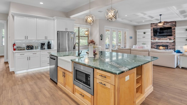 A spacious kitchen with white cabinets, a large island, stainless steel appliances, and pendant lighting.