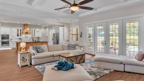 A spacious living room with a large sofa, a coffee table, and a ceiling fan.