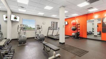 A gym with treadmills, elliptical machines, and weight benches.