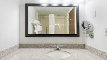 A bathroom with a granite countertop, a sink, a mirror, and a shower curtain.